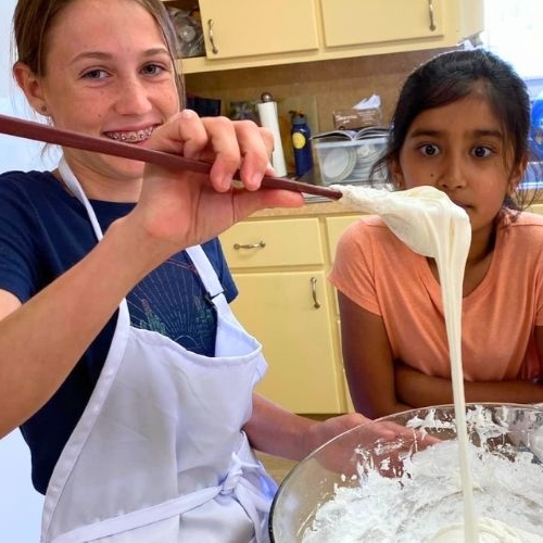Two kids baking together at a Bake Austin class, stretching dough